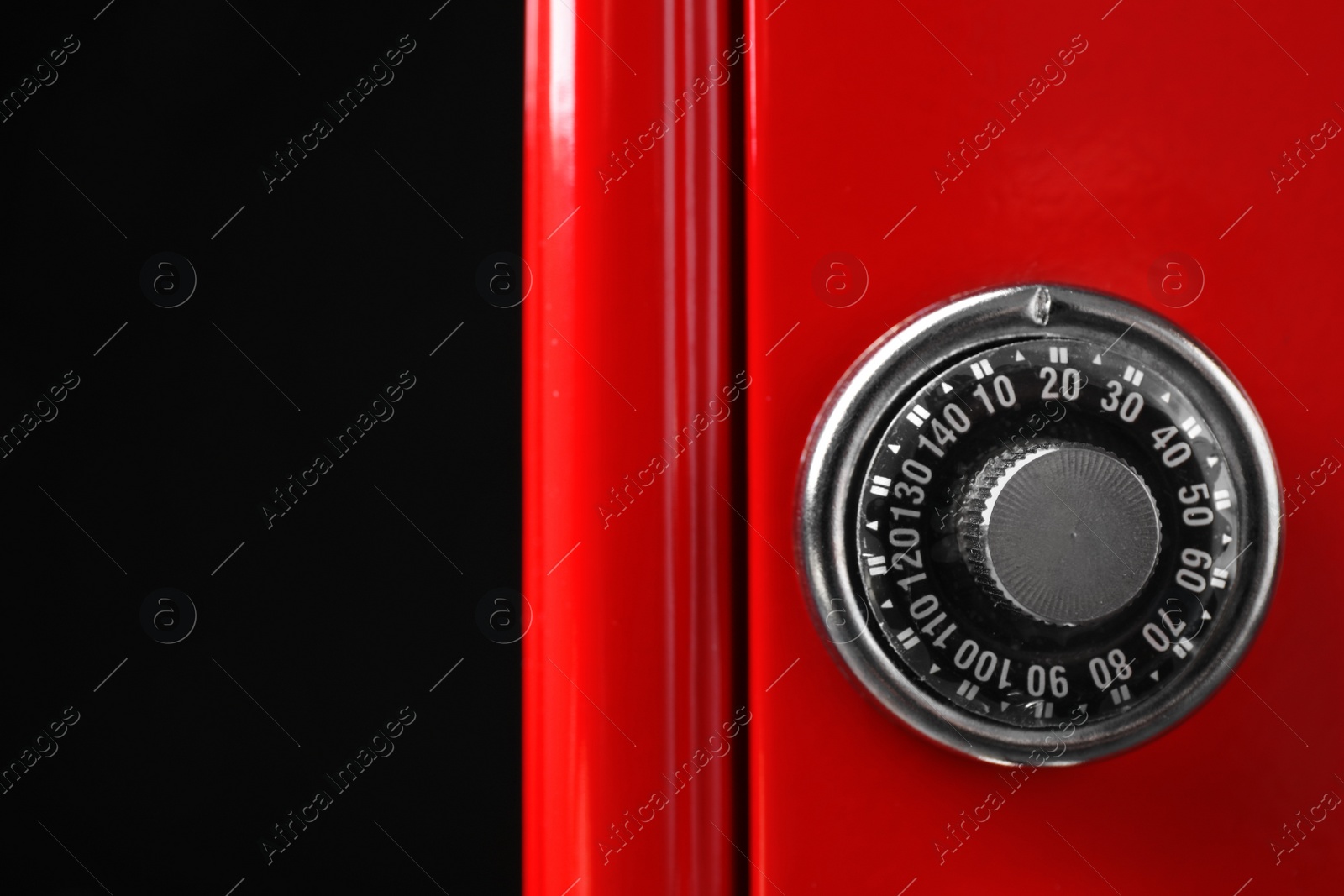 Photo of Red steel safe with mechanical combination lock on black background, closeup