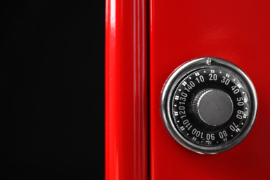 Red steel safe with mechanical combination lock on black background, closeup
