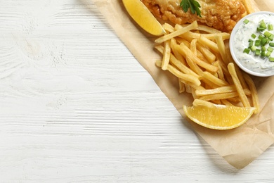 Photo of British traditional fish and potato chips on wooden background, top view with space for text