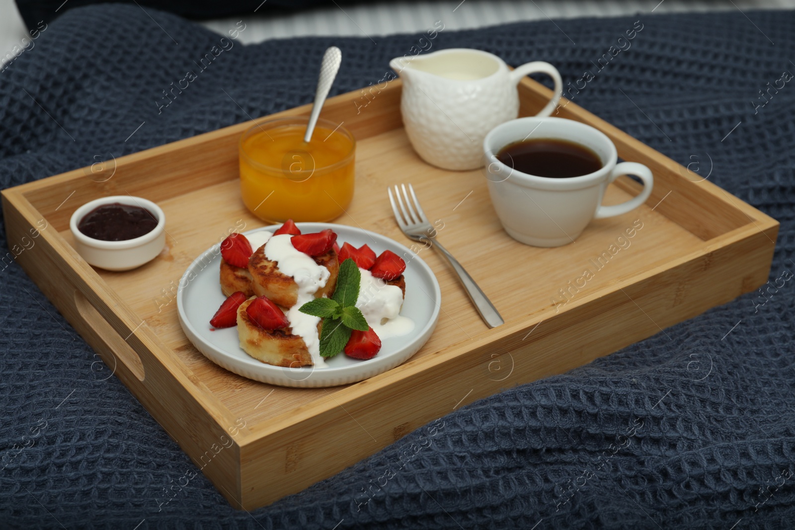 Photo of Cottage cheese pancakes with fresh strawberries, sour cream and mint served for breakfast on wooden tray