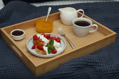 Cottage cheese pancakes with fresh strawberries, sour cream and mint served for breakfast on wooden tray