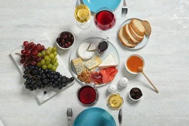 Photo of Wine and snacks served for dinner on light table, top view