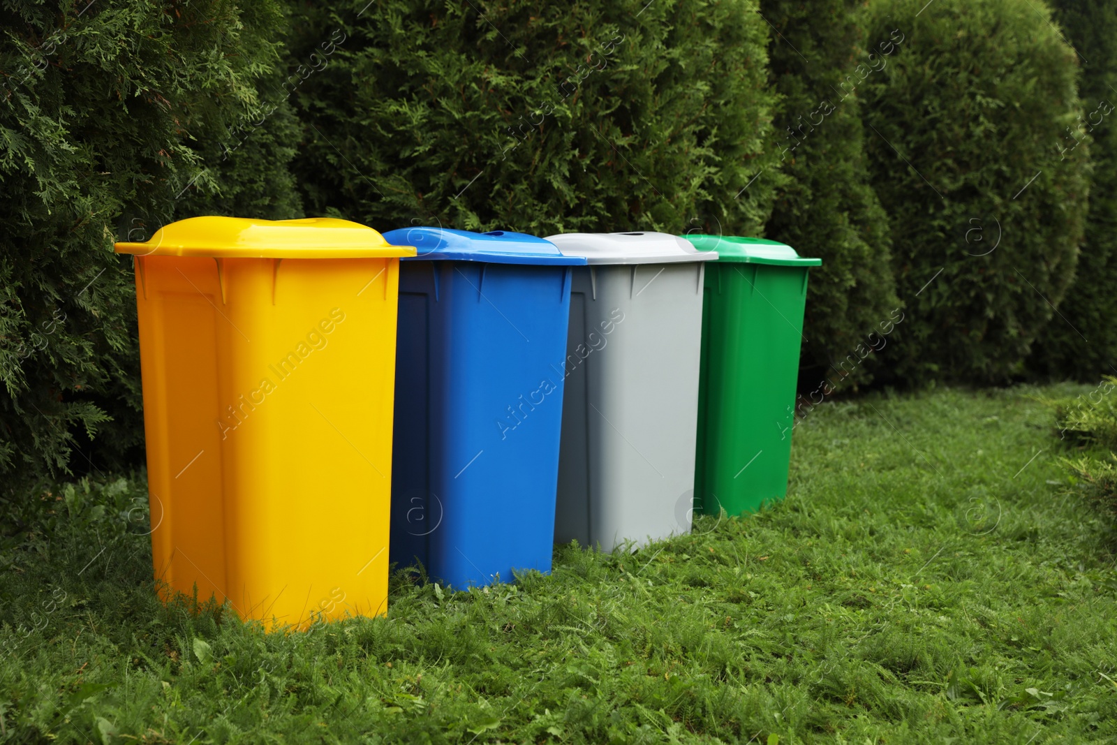 Photo of Many color recycling bins on green grass outdoors, space for text