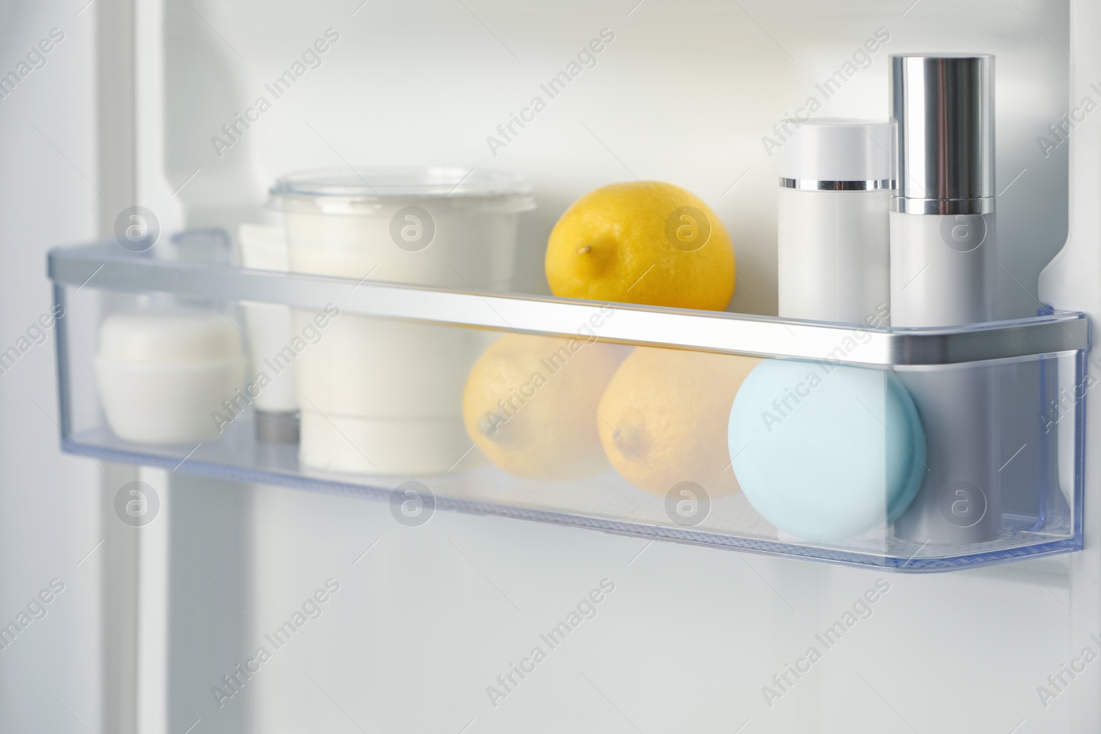 Photo of Different cosmetic products on shelf in refrigerator