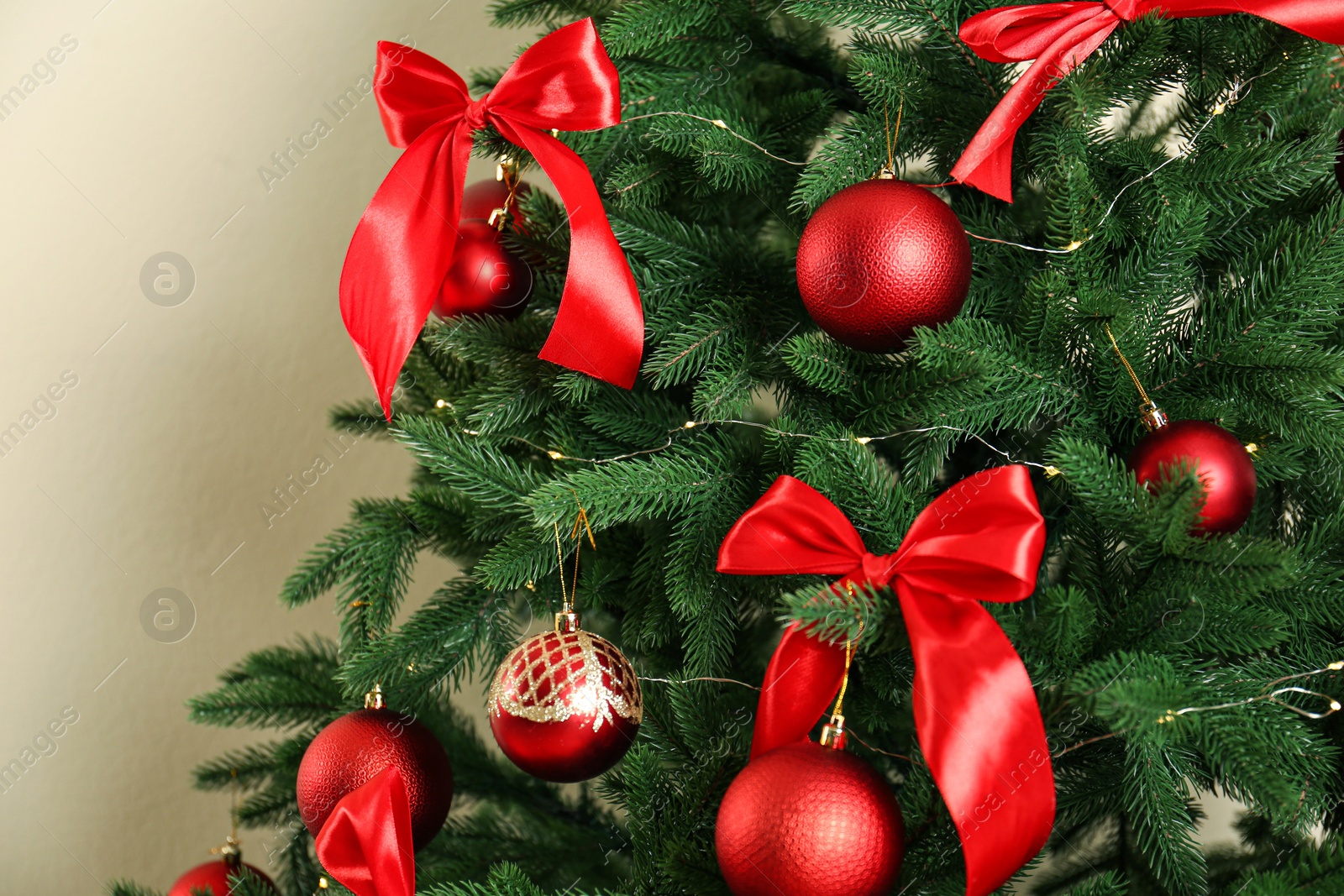 Photo of Decorated Christmas tree on beige background, closeup