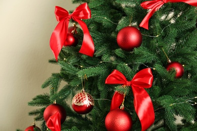 Photo of Decorated Christmas tree on beige background, closeup