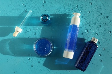 Set of cosmetic products on wet turquoise background, top view