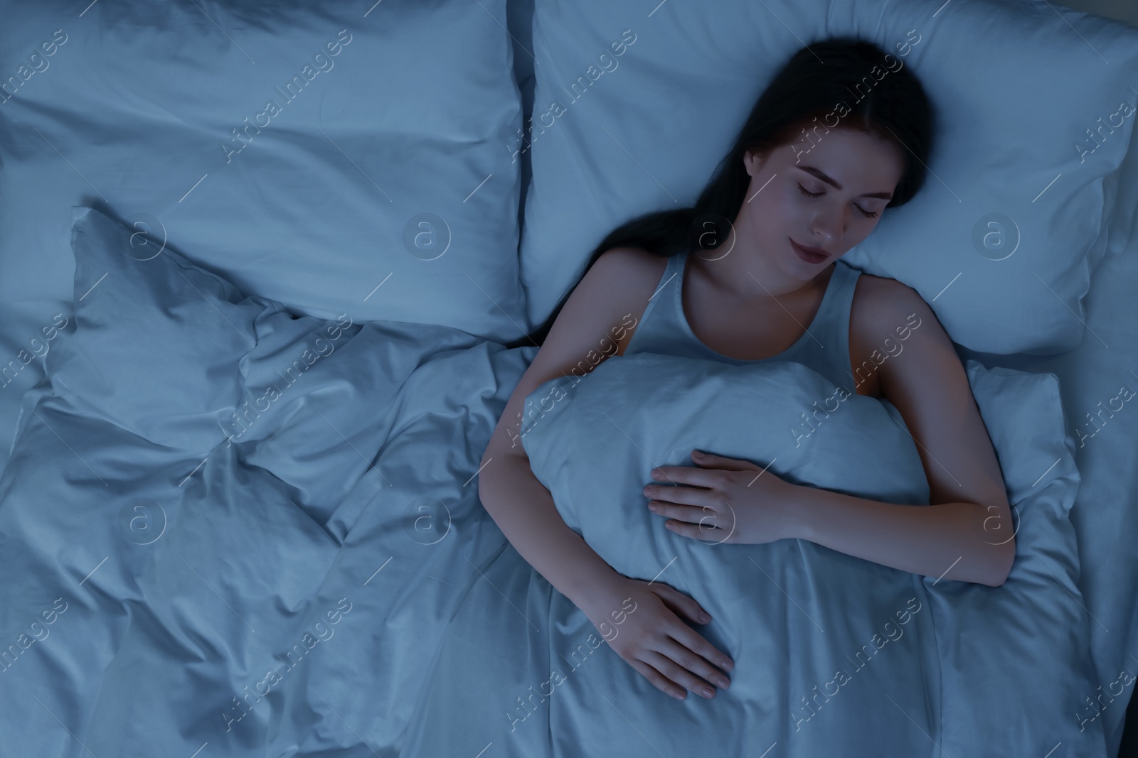 Photo of Beautiful young woman sleeping in bed at night, top view