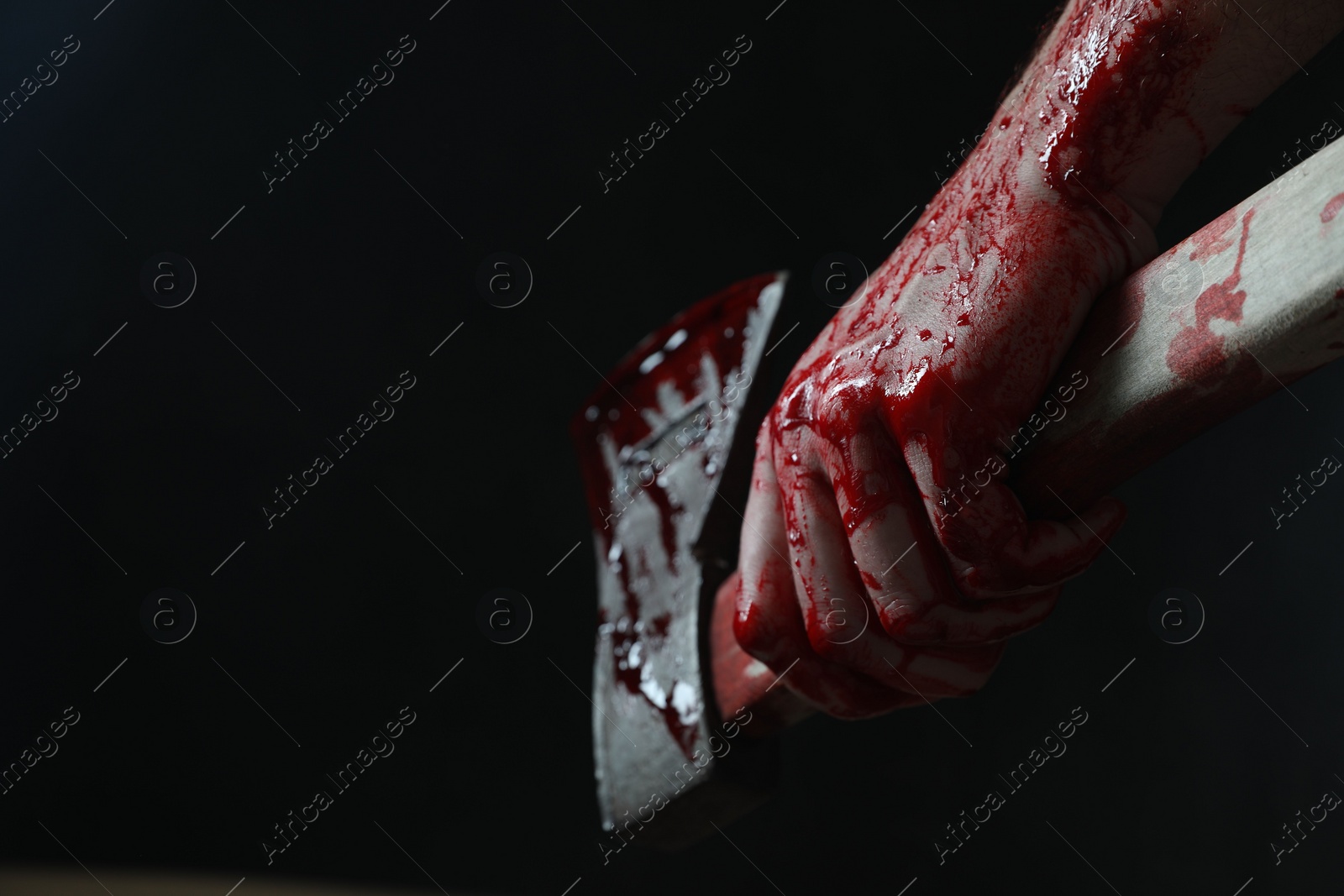 Photo of Man holding bloody axe on black background, closeup. Space for text