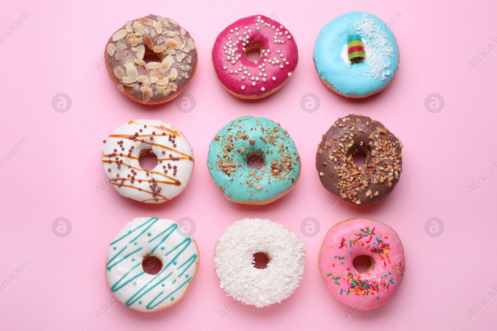 Photo of Different tasty donuts on pink background, flat lay