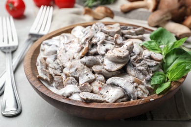 Photo of Wooden bowl with delicious cooked mushrooms on table, closeup