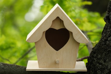 Wooden bird house on tree branch outdoors