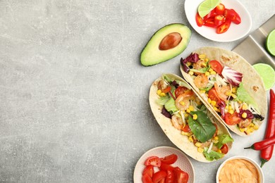Photo of Delicious tacos with shrimps served on light grey table, flat lay. Space for text