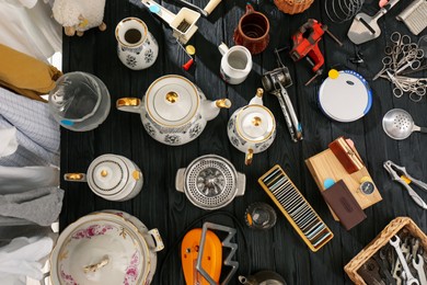 Photo of Many different stuff on black wooden table, flat lay. Garage sale
