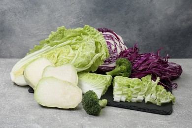 Photo of Different types of cut cabbage on light grey table