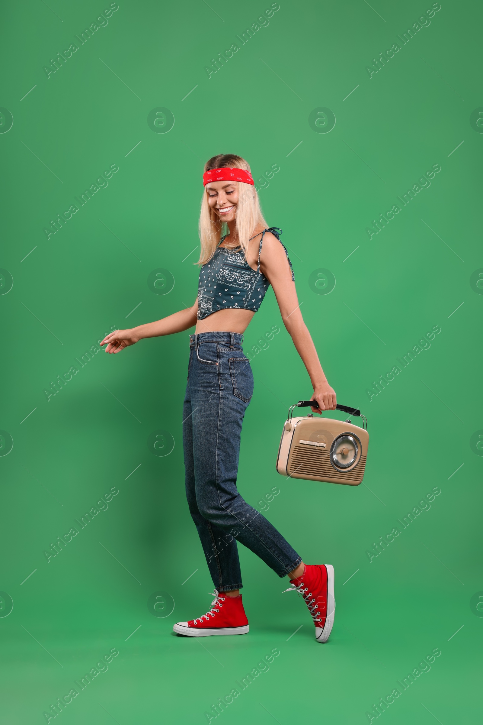 Photo of Happy hippie woman with retro radio receiver on green background