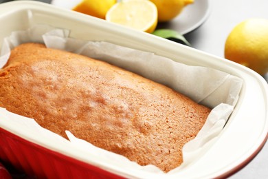 Photo of Tasty lemon cake in baking dish on table, closeup