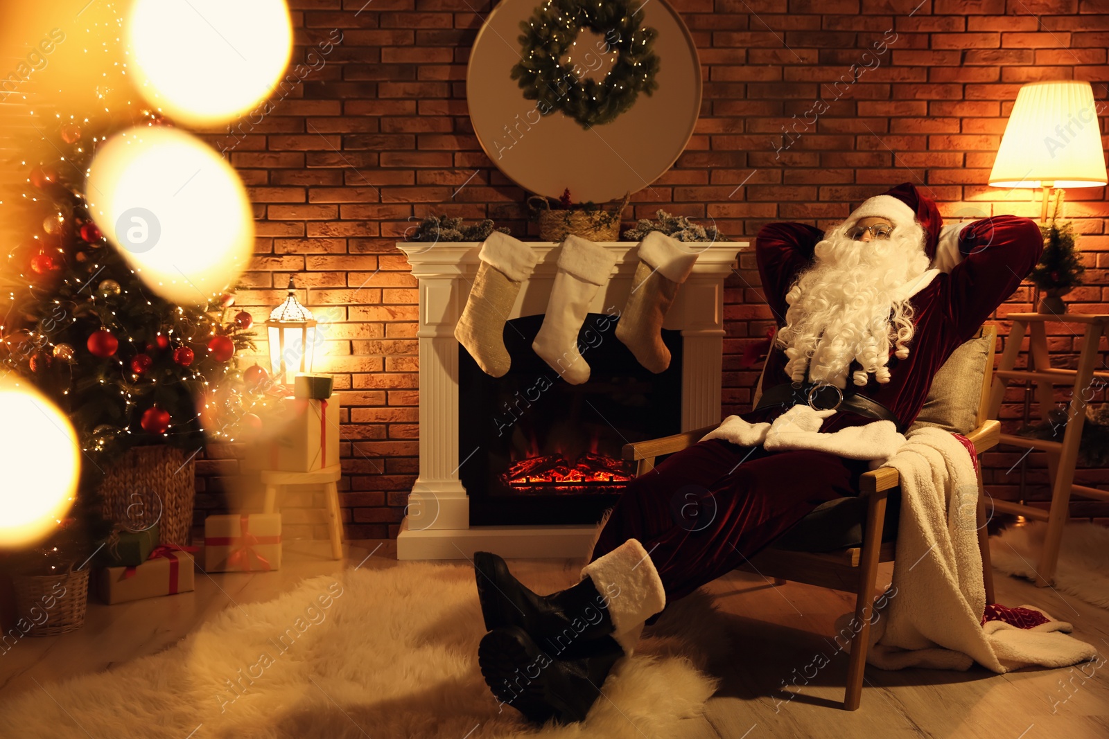 Photo of Santa Claus resting in armchair near fireplace indoors