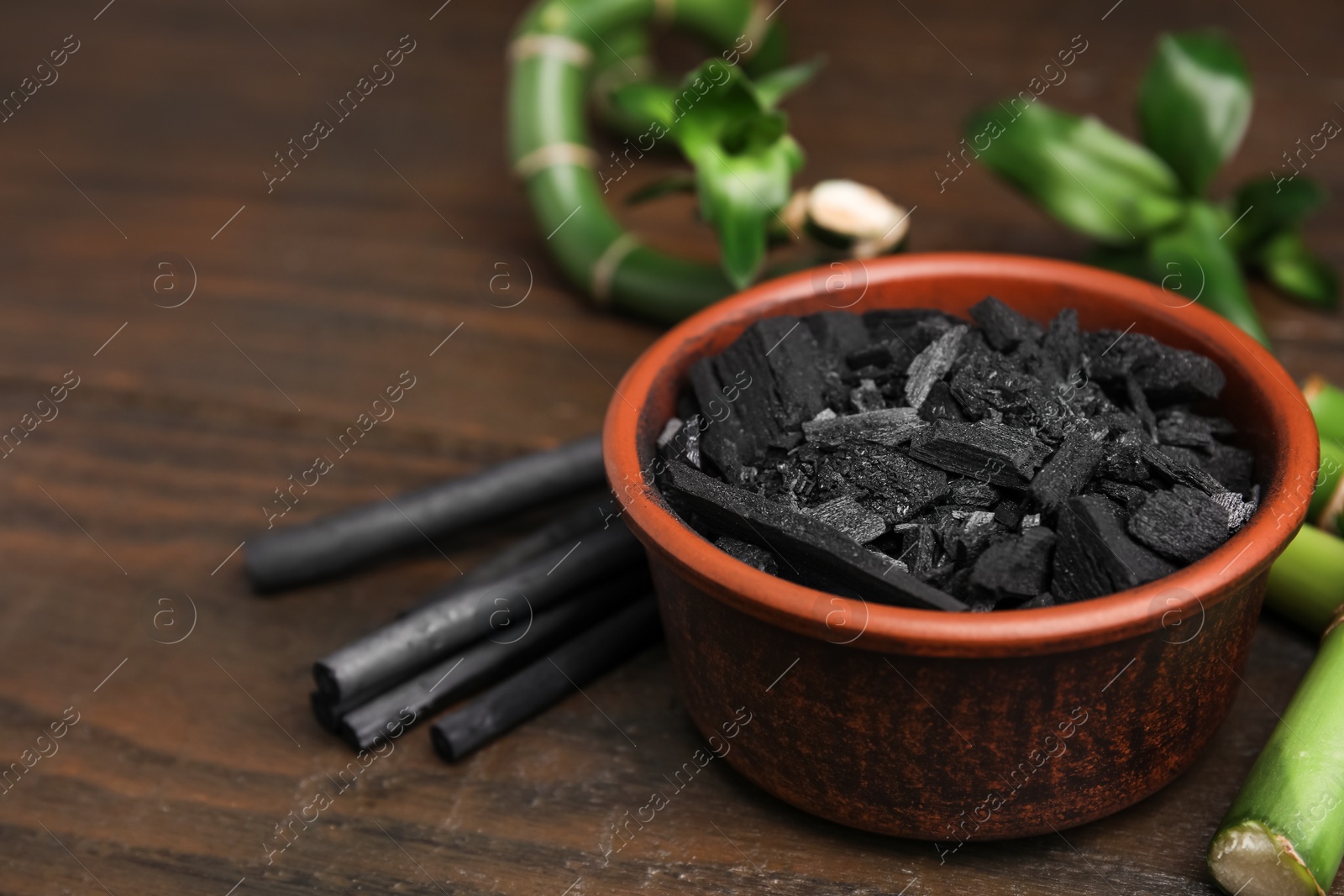 Photo of Fresh bamboo and charcoal on wooden table, closeup. Space for text