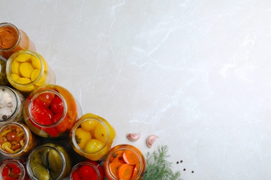 Photo of Jars of pickled vegetables on light table, flat lay. Space for text