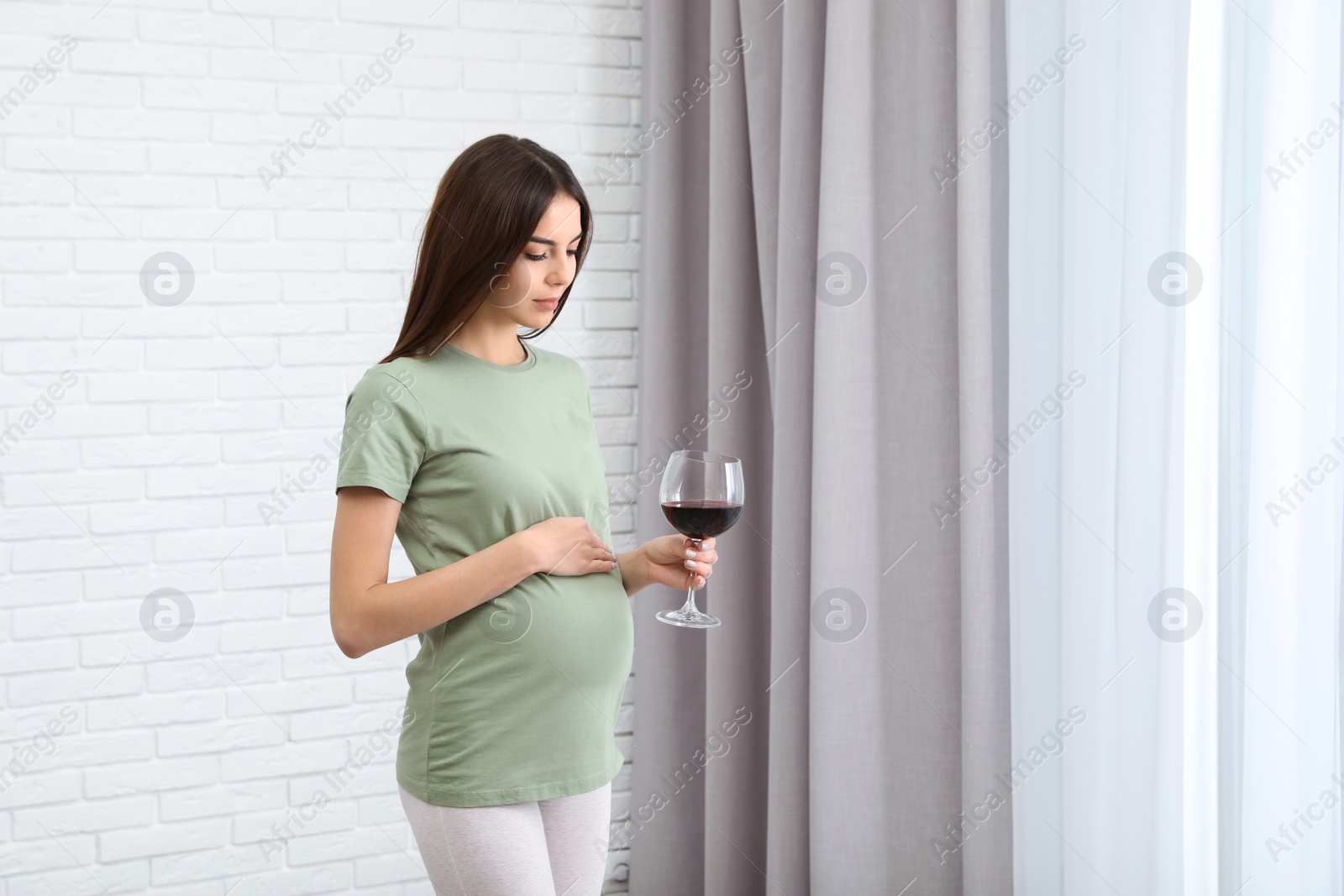 Photo of Future mother with glass of wine indoors, space for text. Alcohol abuse during pregnancy