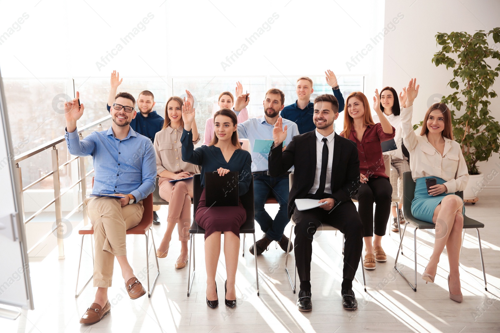 Photo of People raising hands to ask questions at business training indoors