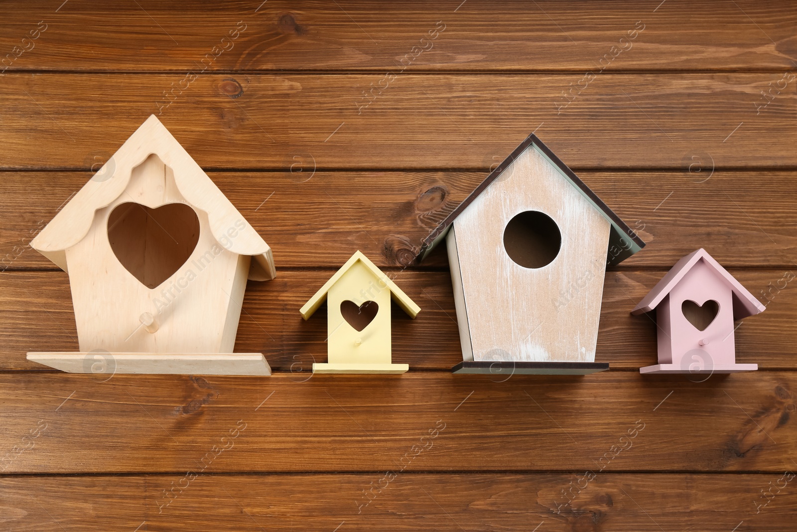 Photo of Collection of handmade bird houses on wooden background, flat lay