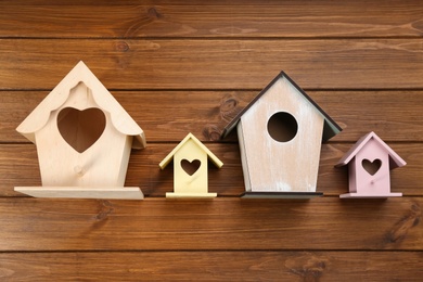 Collection of handmade bird houses on wooden background, flat lay