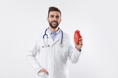 Photo of Doctor with stethoscope and model of heart on white background. Cardiology concept