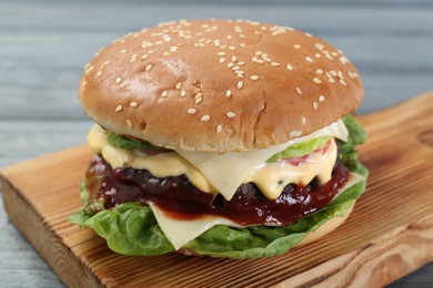 Photo of Tasty homemade cheeseburger with lettuce on grey table, closeup