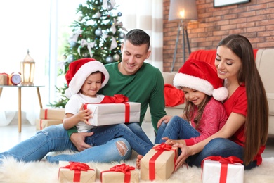 Photo of Happy parents and children exchanging gifts near Christmas tree at home