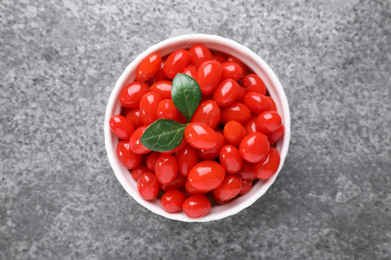 Photo of Bowl with fresh goji berries on grey background, top view