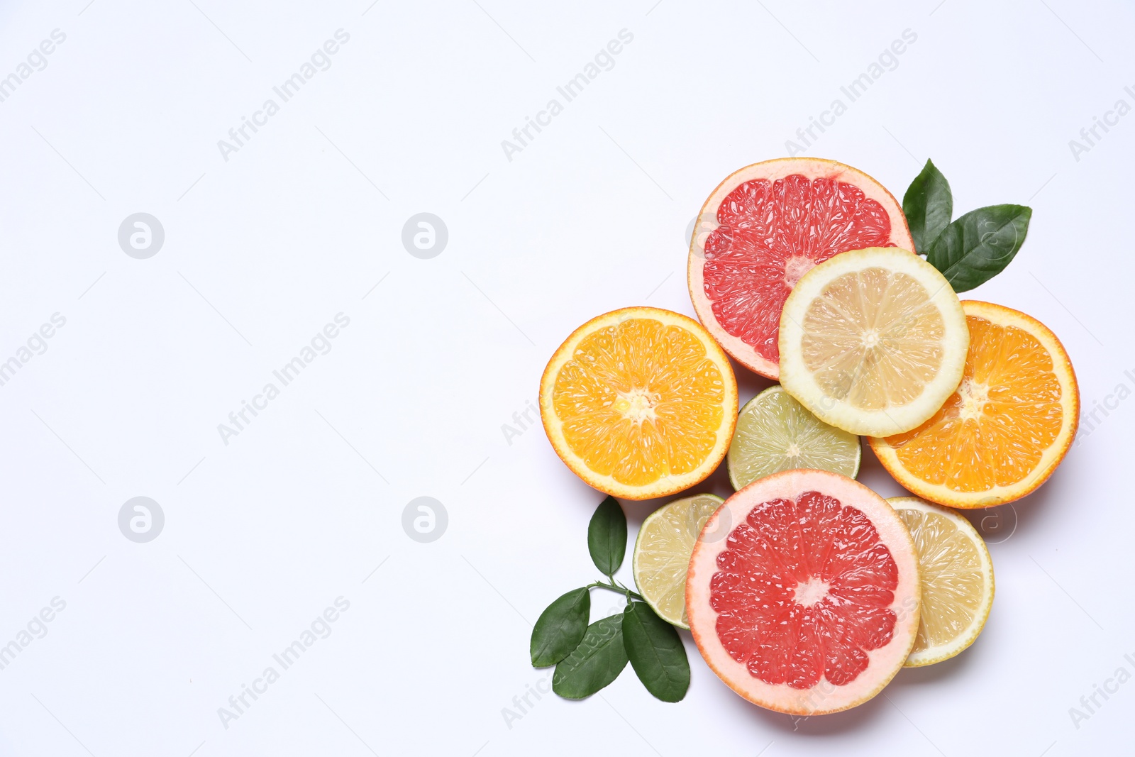 Photo of Different cut citrus fruits and leaves on white table, flat lay. Space for text