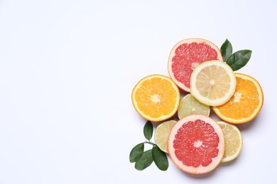 Different cut citrus fruits and leaves on white table, flat lay. Space for text