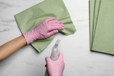 Photo of Woman in gloves cleaning light table with paper towel and detergent, top view