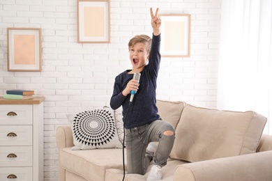 Photo of Cute boy with microphone on sofa in living room