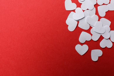 Photo of White paper hearts on red background, flat lay. Space for text