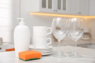 Photo of Set of clean dishes and cleaning product on table in stylish kitchen