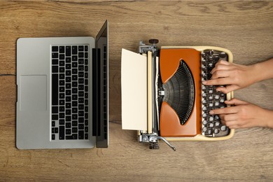 Photo of Woman using old typewriter near laptop at wooden table, top view. Concept of technology progress