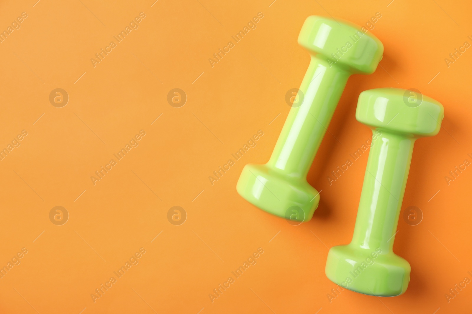 Photo of Bright dumbbells and space for text on color background, flat lay. Home fitness