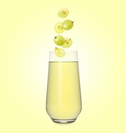 Image of Freshly made grape juice on pale yellow background. Cut and whole berries falling into glass