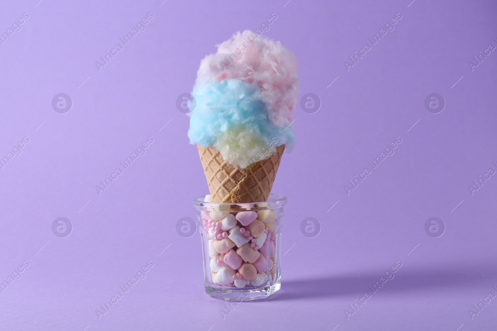 Photo of Sweet cotton candy in waffle cone on purple background