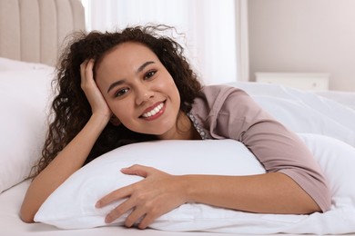 Photo of Happy African American woman lying on bed at home