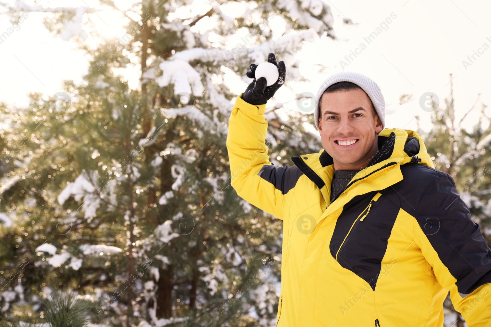 Photo of Happy man throwing snowball outdoors on winter day