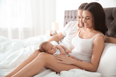 Happy couple with their newborn baby on bed