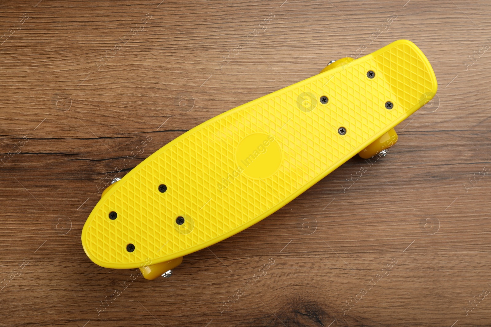 Photo of Yellow skateboard on wooden background, top view. Sport equipment