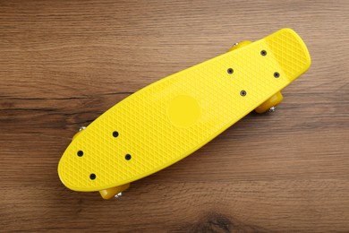 Photo of Yellow skateboard on wooden background, top view. Sport equipment