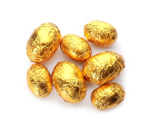 Chocolate eggs wrapped in golden foil on white background, top view
