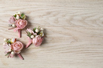 Stylish pink boutonnieres on white wooden table, flat lay. Space for text