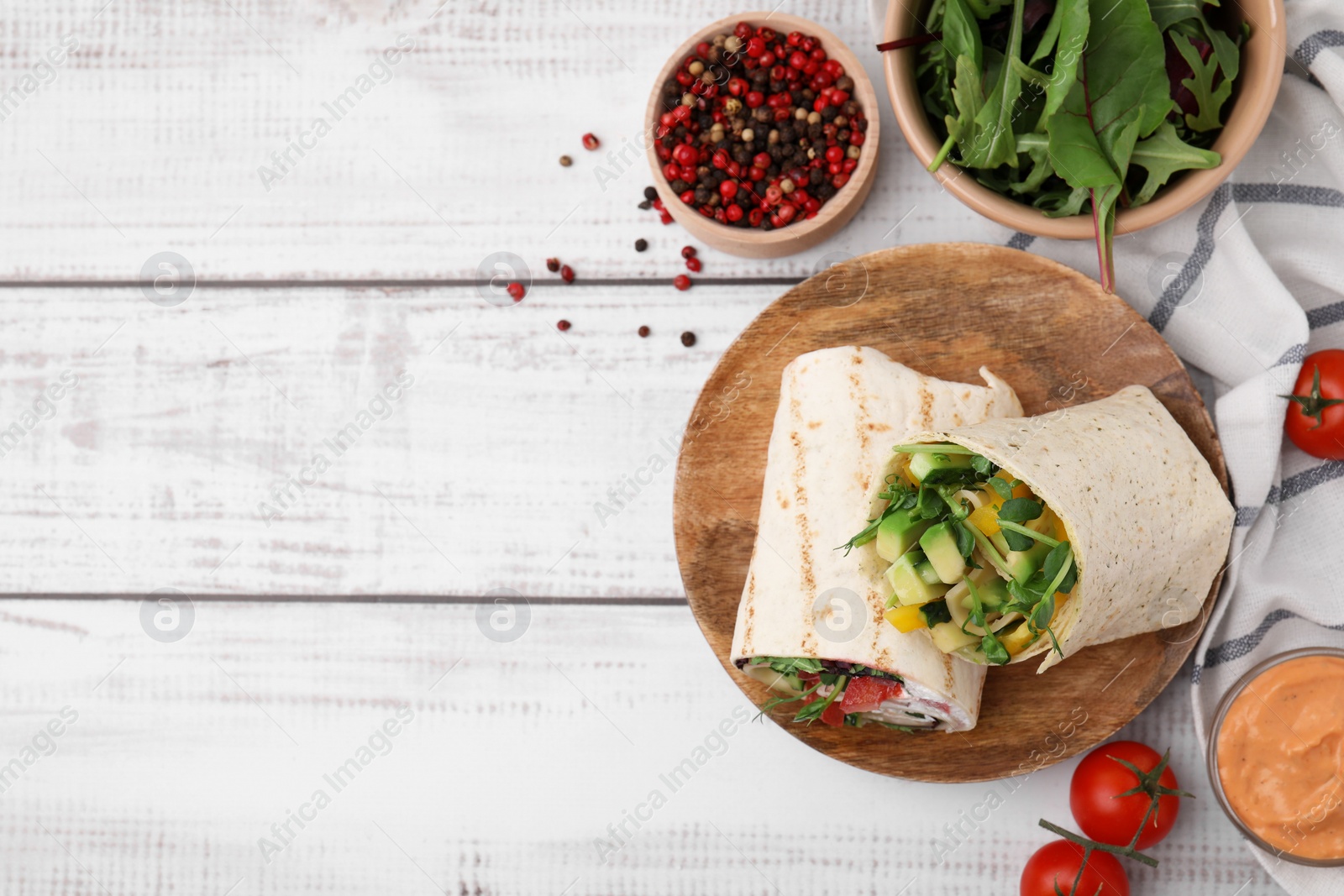 Photo of Delicious sandwich wraps with fresh vegetables, tomatoes, sauce and peppercorns on white wooden table, flat lay. Space for text
